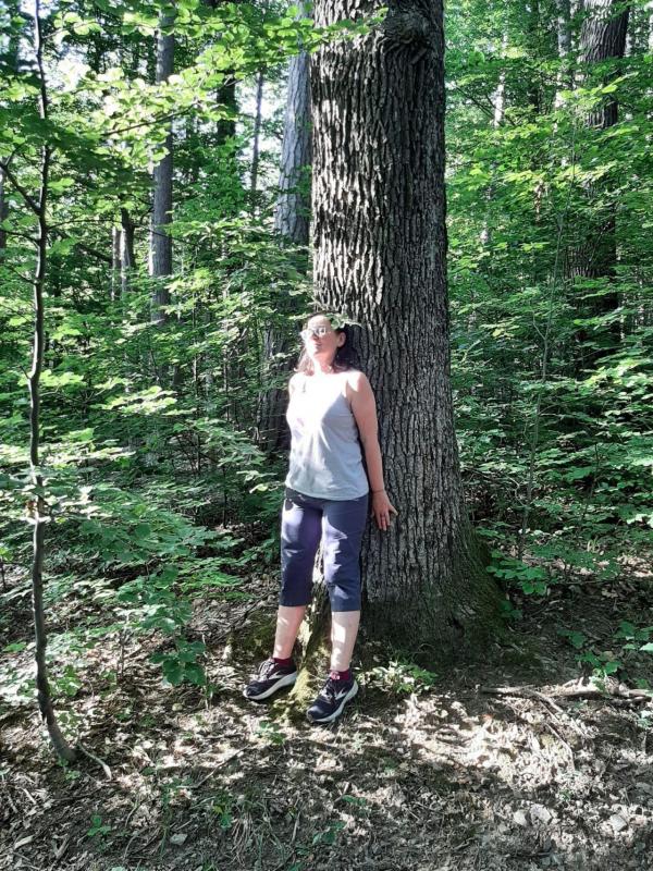 Frau lehnt sich an Baum